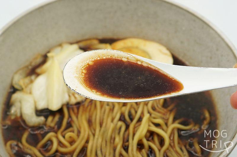 生ラーメンすすきのブラック｜いそのかづお　スープをレンゲですくった様子