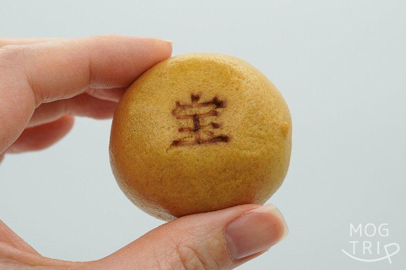 千秋庵総本家「宝来まんじゅう」を手に持っている様子