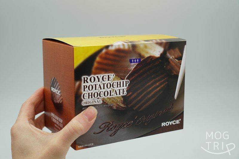 ROYCE’（ロイズ）のポテトチップチョコレートの箱を手に持っている様子